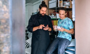 A cheif and waitress using their mobile phones to manage business operations.